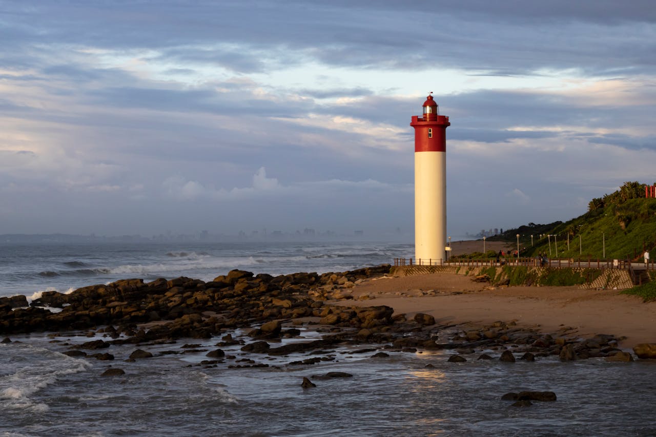 Scenic view of Umhlanga Lighthouse on the rocky shore at sunset in South Africa.